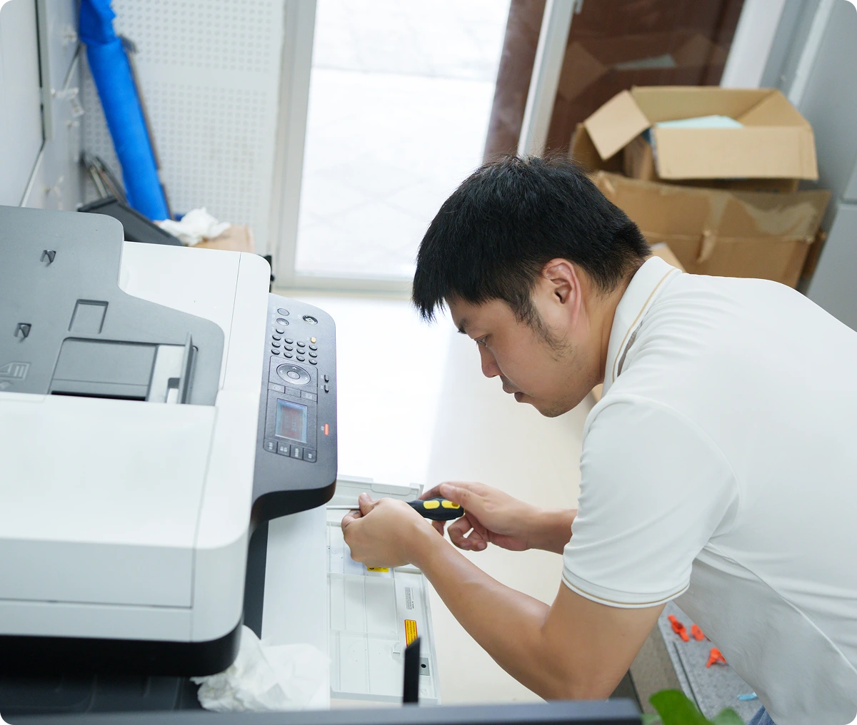 Man repairing a printer in an office.
