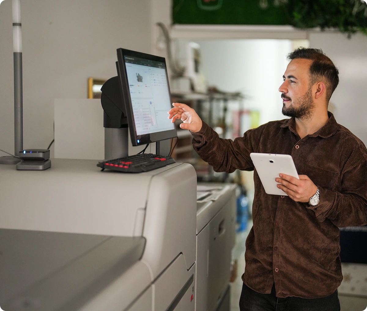 Man operating printer with tablet in hand.