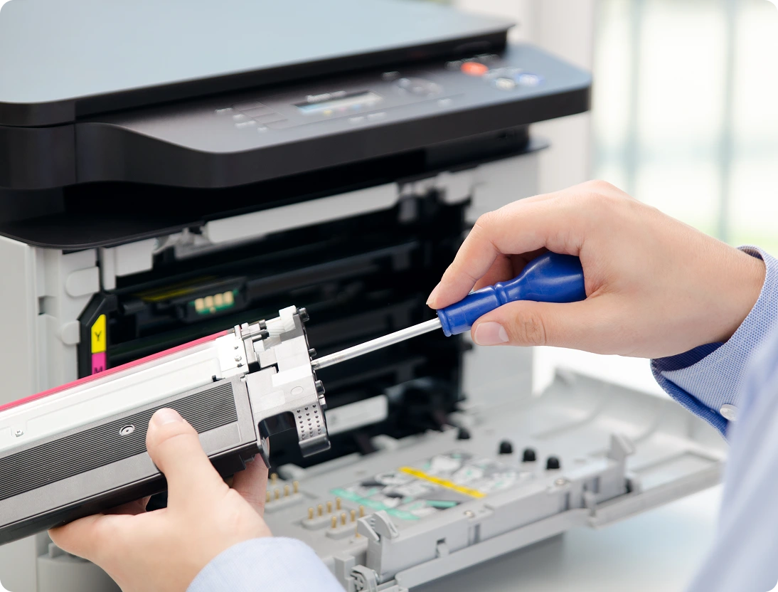 Person fixing a printer with screwdriver.