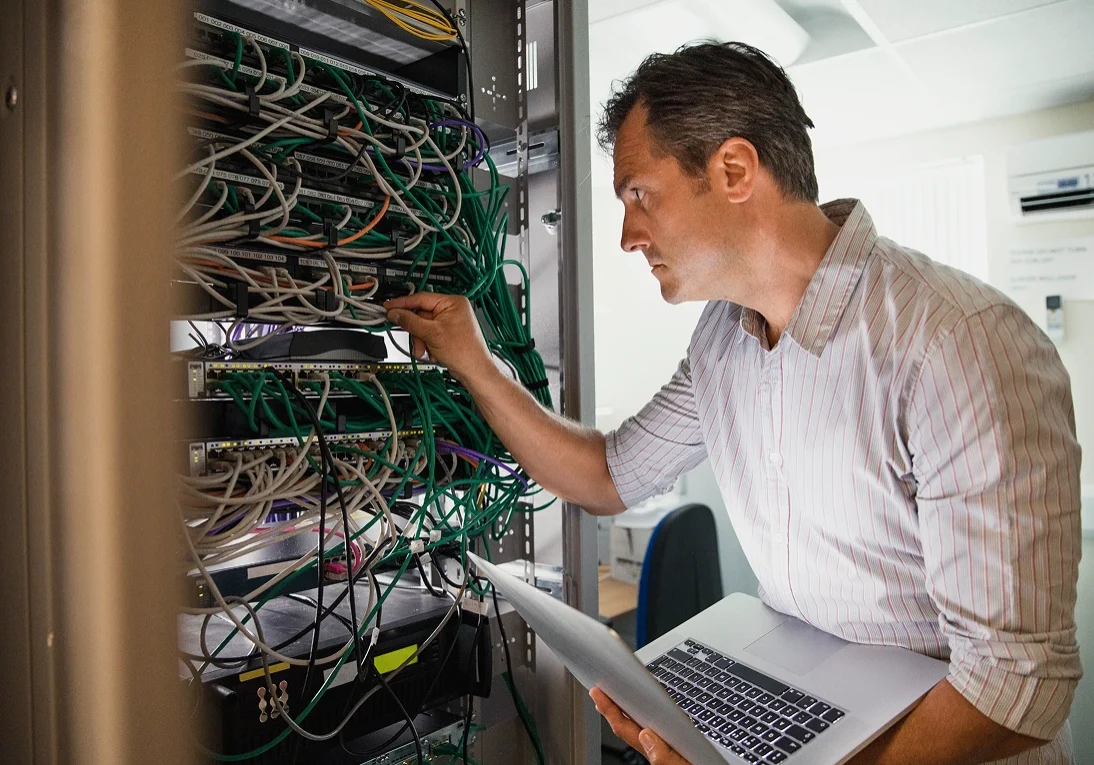 Man working on server cables with laptop.